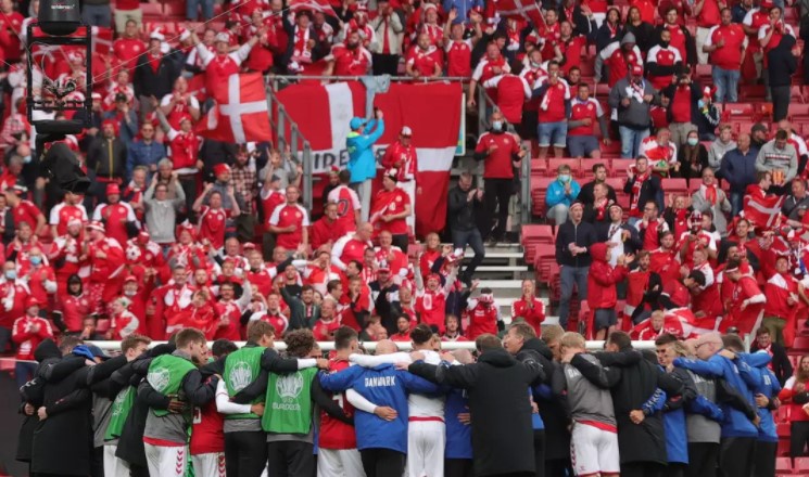 Jogadores e comissão técnica da Dinamarca se abraçam diante da torcida antes do reinício do jogo contra a Finlândia depois do mal súbito de Eriksen em campo